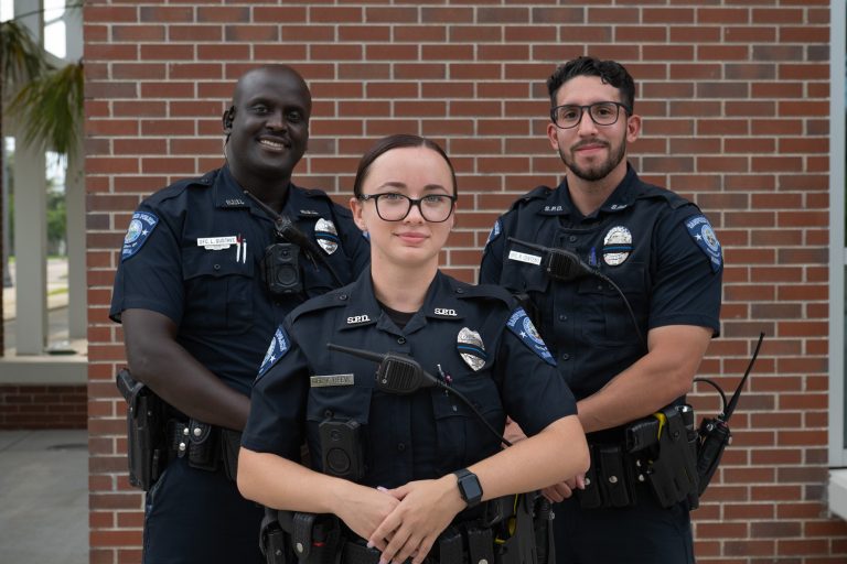 Three Sanford Officers standing in front of brick wall.